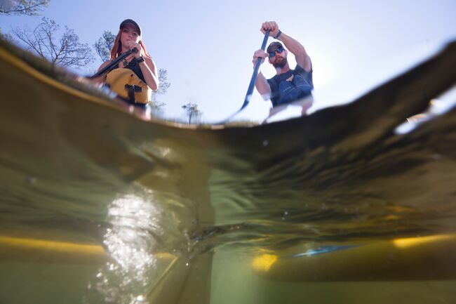 Two people paddle boards in a half-submerged photo