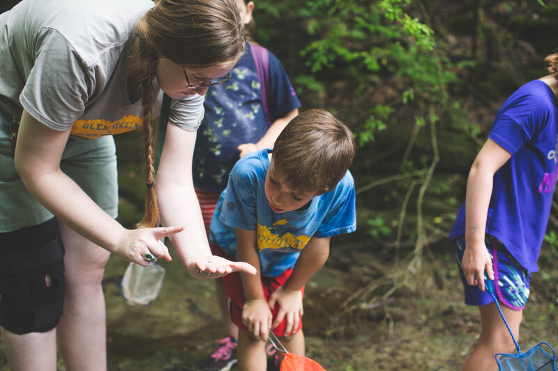 A camp counselor shows a boy a bug.