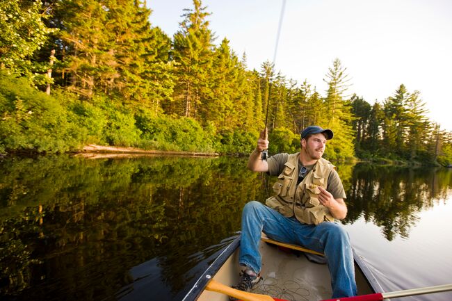 A man fly fishes from a canoe