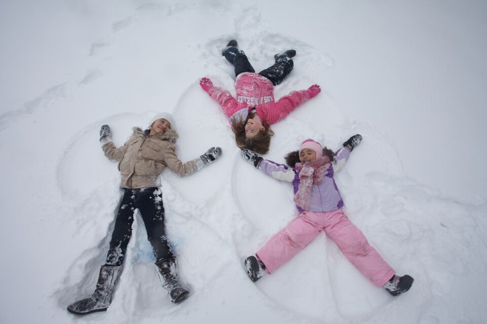 Three bundled-up girls make snow angels at Wilder Park in St. Paul, MN.